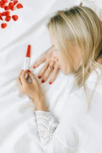 woman laying next to pregnancy test on her bed